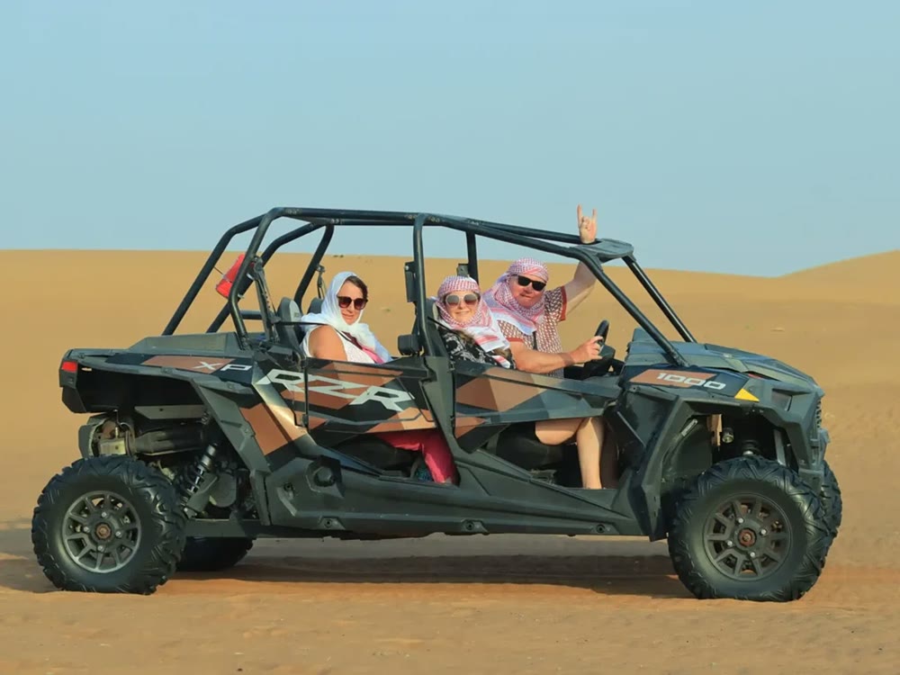Family of four seated in a 4 seater Polaris RZR 1000 dune buggy on the Dubai sand